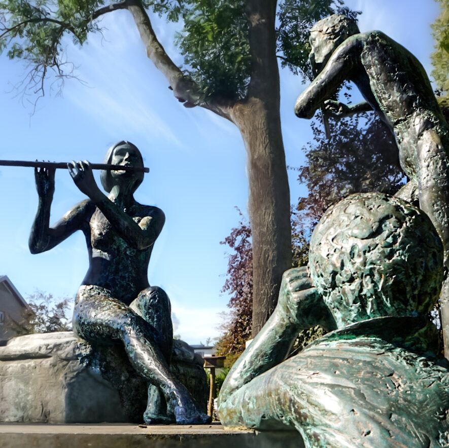 Drie bronzen beelden van figuren, waarvan één een fluit bespeelt, onder een boom met een helderblauwe lucht op de achtergrond. De beelden hebben een groenige patina.